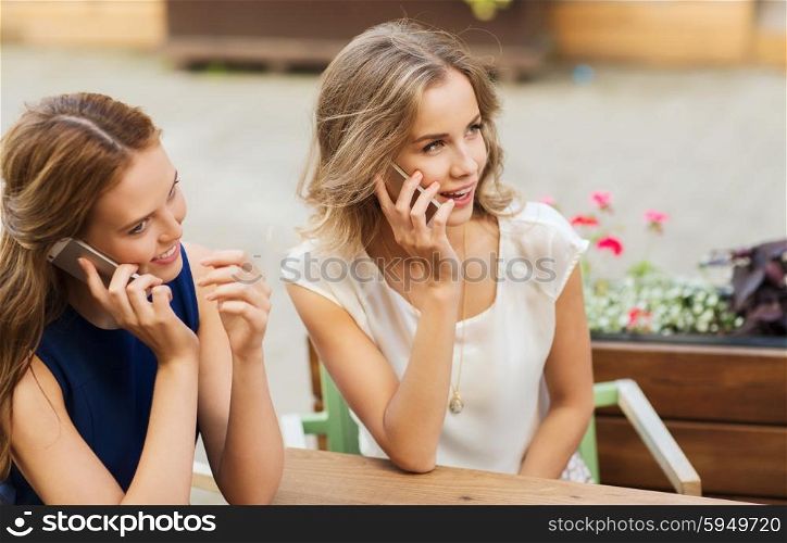 technology, lifestyle, communication and people concept - happy young women or teenage girls calling on smartphones at cafe outdoors