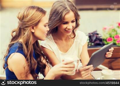 technology, lifestyle, friendship and people concept - happy young women or teenage girls with tablet pc computer drinking coffee at outdoor cafe