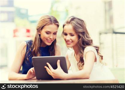 technology, lifestyle, friendship and people concept - happy young women or teenage girls with tablet pc computer at outdoor cafe