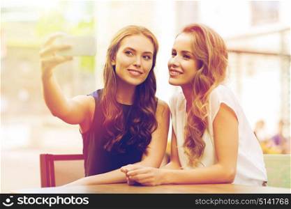technology, lifestyle, friendship and people concept - happy young women or teenage girls with smartphone taking selfie at outdoor cafe. happy women with smartphone taking selfie at cafe