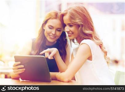 technology, lifestyle, friendship and people concept - happy young women or teenage girls with tablet pc computer at outdoor cafe. happy young women with tablet pc at outdoor cafe