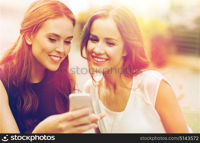 technology, lifestyle, friendship and people concept - happy young women or teenage girls with smartphone at outdoor cafe. happy young women with smartphone at outdoor cafe