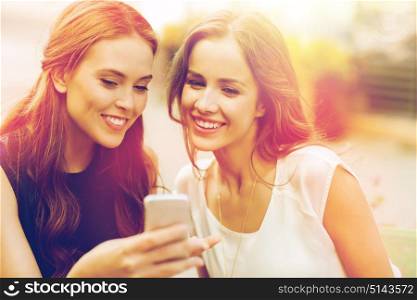 technology, lifestyle, friendship and people concept - happy young women or teenage girls with smartphone at outdoor cafe. happy young women with smartphone at outdoor cafe
