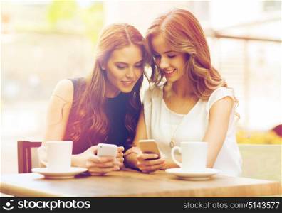 technology, lifestyle, friendship and people concept - happy young women or teenage girls with smartphones and coffee cups at cafe outdoors. women with smartphones and coffee at outdoor cafe