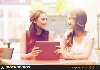 technology, lifestyle, friendship and people concept - happy young women or teenage girls with tablet pc at cafe outdoors. happy young women or teenage girls with tablet pc
