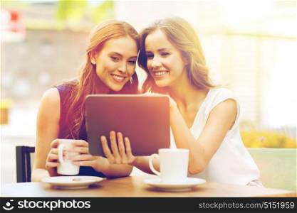 technology, lifestyle, friendship and people concept - happy young women or teenage girls with tablet pc computer drinking coffee at outdoor cafe. young women with tablet pc and coffee at cafe