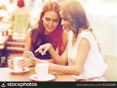 technology, lifestyle, friendship and people concept - happy young women or teenage girls with smartphone and coffee cups at outdoor cafe. young women with smartphone and coffee at cafe