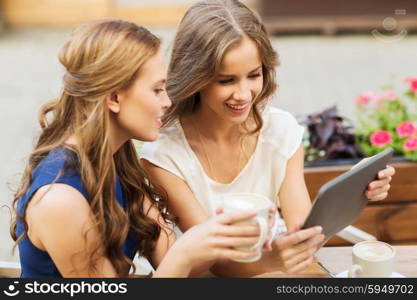 technology, lifestyle, friendship and people concept - happy young women or teenage girls with tablet pc computer drinking coffee at outdoor cafe