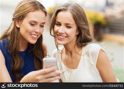 technology, lifestyle, friendship and people concept - happy young women or teenage girls with smartphone at outdoor cafe