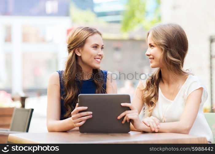 technology, lifestyle, friendship and people concept - happy young women or teenage girls with tablet pc at cafe outdoors