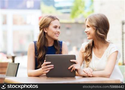 technology, lifestyle, friendship and people concept - happy young women or teenage girls with tablet pc at cafe outdoors