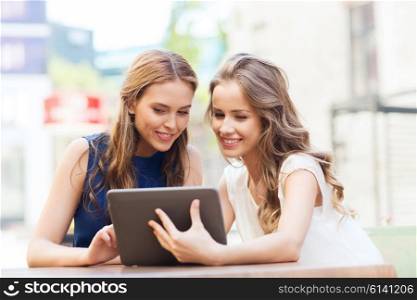 technology, lifestyle, friendship and people concept - happy young women or teenage girls with tablet pc computer at outdoor cafe