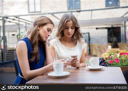 technology, lifestyle, internet addiction and people concept - young women with smartphones drinking coffee at cafe outdoors. young women with smartphones and coffee at cafe. young women with smartphones and coffee at cafe