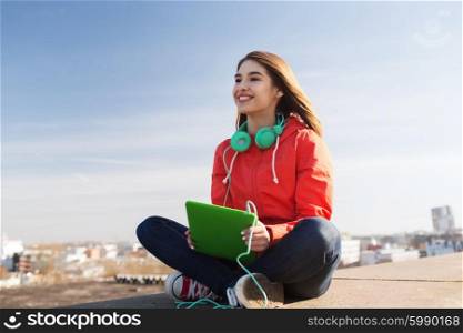 technology, lifestyle, music and people concept - smiling young woman or teenage girl with tablet pc computer and headphones outdoors