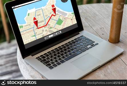 technology, location, navigation, business and modern life concept- close up of open laptop computer with gps navigator map on screen on table at hotel terrace