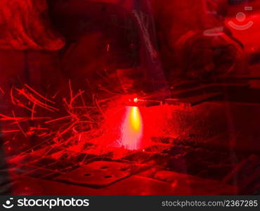 Technology, machines concept. Industrial laser cutting steel metal with bright red sparks. Laser cutting steel metal with bright sparks