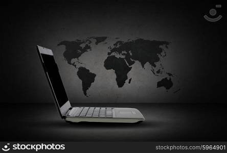 technology, mass media and global business concept - open laptop computer with world map over dark gray background