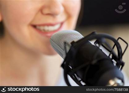 technology, mass media and people concept - close up of woman with microphone talking and recording podcast at studio. close up of woman talking to microphone