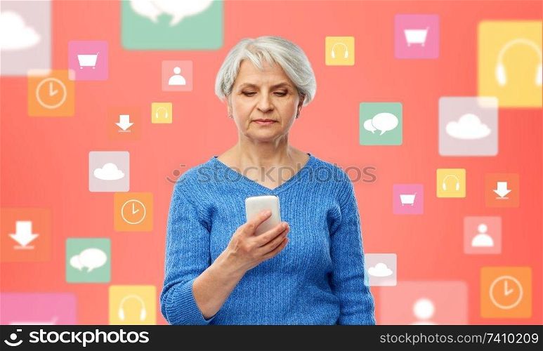technology, media and old people concept - senior woman using smartphone over mobile app icons on living coral background. senior woman with smartphone over mobile app icons