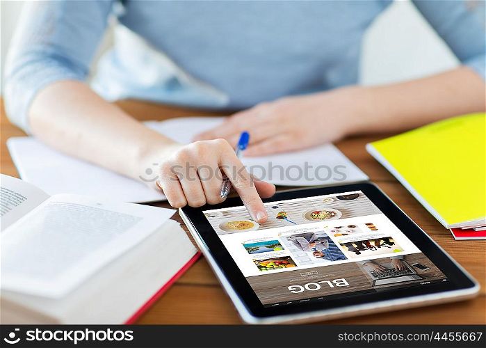 technology, media, internet and people concept - close up of student woman with blog web page on tablet pc computer screen and notebook at home