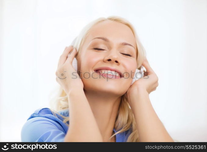 technology, music and happiness concept - smiling young girl in headphones at home