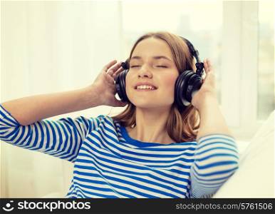 technology, music and happiness concept - smiling young girl in headphones at home