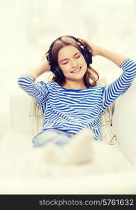 technology, music and happiness concept - smiling young girl in headphones at home