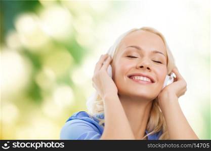 technology, music and happiness concept - smiling young girl in headphones outdoors
