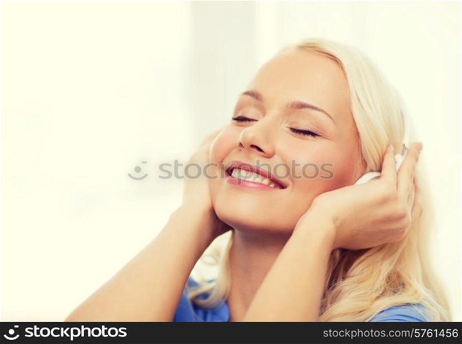 technology, music and happiness concept - smiling young woman in headphones at home