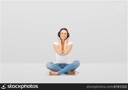 technology, music and happiness concept - smiling young woman or teen girl in headphones over gray background