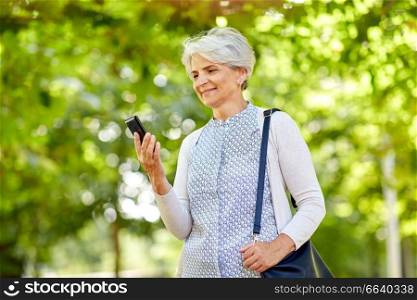 technology, old age and people concept - happy senior woman with smartphone at summer park. happy senior woman with smartphone at summer park
