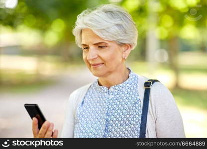 technology, old age and people concept - happy senior woman with smartphone at summer park. happy senior woman with smartphone at summer park