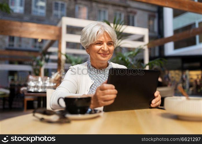 technology, old age and people concept - happy senior woman with tablet pc and coffee at street cafe. senior woman with tablet pc and coffee at cafe