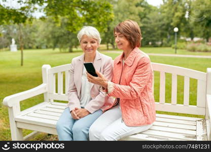 technology, old age and people concept - happy senior women or female friends with smartphone at summer park. happy senior women with smartphone at summer park