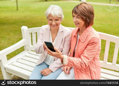 technology, old age and people concept - happy senior women or female friends with smartphone at summer park. happy senior women with smartphone at summer park