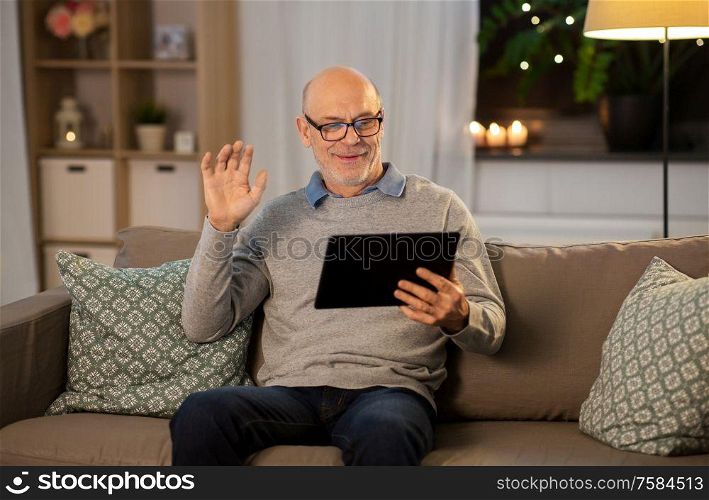 technology, old age and people concept - happy smiling bald senior man with tablet pc computer having video call at home in evening. old man with tablet pc having video call at home