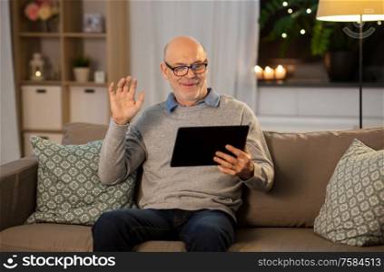 technology, old age and people concept - happy smiling bald senior man with tablet pc computer having video call at home in evening. old man with tablet pc having video call at home