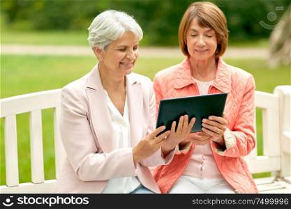 technology, old age and people concept - senior women with tablet pc computer at summer park. senior women with tablet pc at summer park