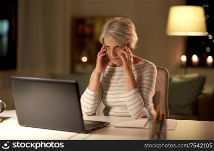 technology, old age and stress concept - tired or stressed senior woman with laptop computer at home in evening. tired senior woman with laptop at home at night