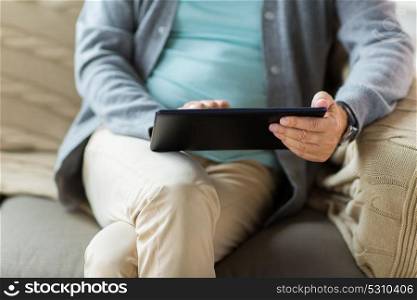 technology, old age, people and lifestyle concept - close up of senior man with tablet pc computer sitting on sofa. close up of senior man with tablet pc on sofa