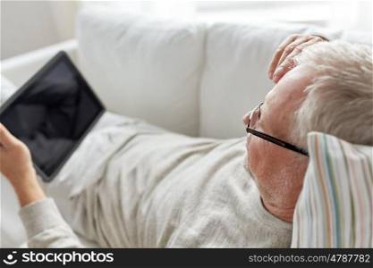 technology, old age, people and lifestyle concept - senior man with tablet pc computer lying on sofa at home