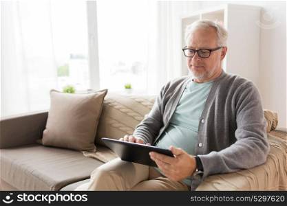 technology, old age, people and lifestyle concept - senior man with tablet pc computer sitting on sofa at home. senior man with tablet pc sitting on sofa at home