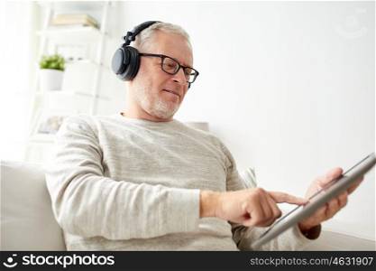 technology, old people, lifestyle and distance learning concept - happy senior man with tablet pc computer and headphones listening to music at home