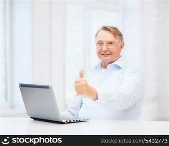 technology, oldness and lifestyle concept - old man in eyeglasses with laptop computer at home showing thumbs up