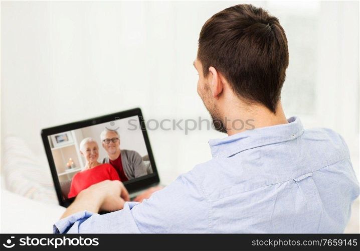 technology, online communication and self isolation concept - young man having video call with his family on laptop computer at home on christmas. man with laptop having video call with his family