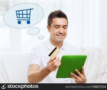 technology, online, sale and people concept - happy man with tablet pc computer, credit card and shopping trolley icon at home