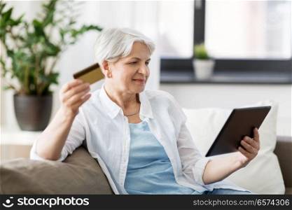 technology, online shopping, age and people concept - senior woman with tablet pc computer and credit or bank card at home. senior woman with tablet pc and credit card
