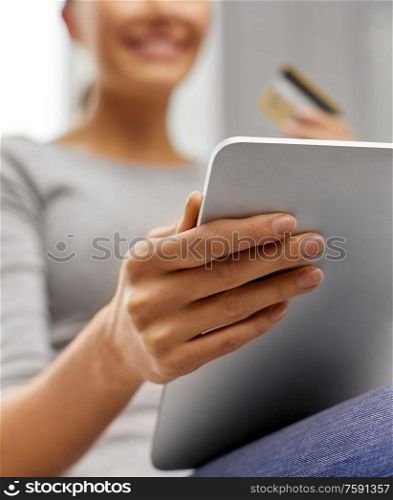 technology, online shopping and people concept - close up of happy woman with tablet pc and credit card sitting on sofa at home. woman with tablet pc and credit card at home