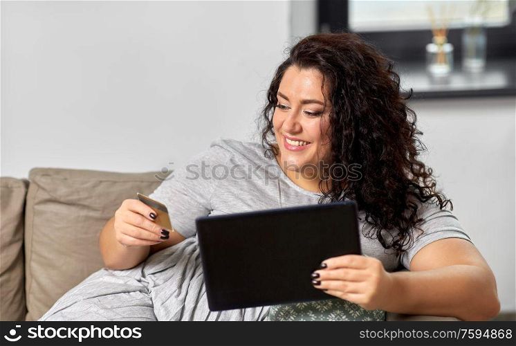 technology, online shopping and people concept - happy smiling woman with tablet pc computer and credit card on sofa at home. woman with tablet pc and credit card at home