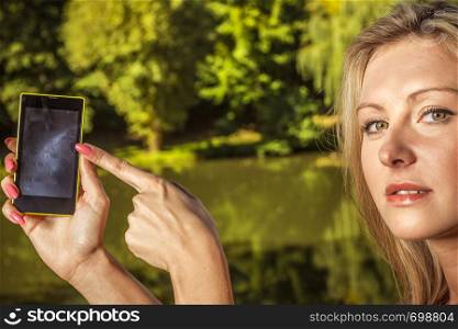 Technology, outdoor relaxation concept. Woman sitting in park, relaxing and using mobile phone, spending her leisure time outside. Woman sitting in park, relaxing and using phone